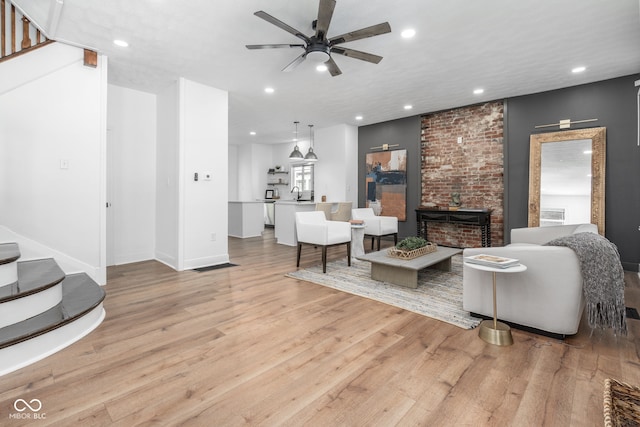 living area with recessed lighting, a fireplace, a ceiling fan, stairs, and light wood-type flooring