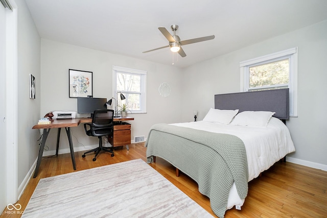 bedroom featuring baseboards, visible vents, ceiling fan, and wood finished floors