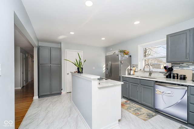 kitchen featuring recessed lighting, gray cabinets, appliances with stainless steel finishes, a sink, and a kitchen island