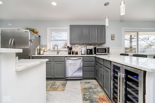 kitchen featuring wine cooler, gray cabinetry, appliances with stainless steel finishes, a sink, and a peninsula