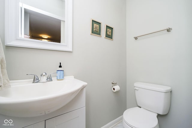 half bath with vanity, toilet, and baseboards