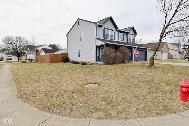 traditional home with a porch, fence, a garage, driveway, and a front lawn