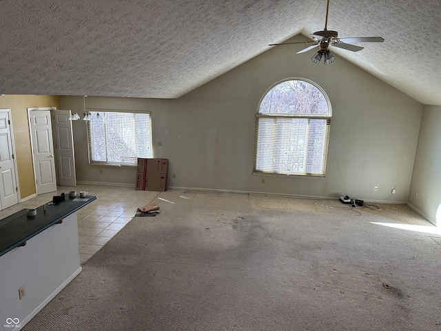 unfurnished living room with a healthy amount of sunlight, light carpet, a textured ceiling, and lofted ceiling