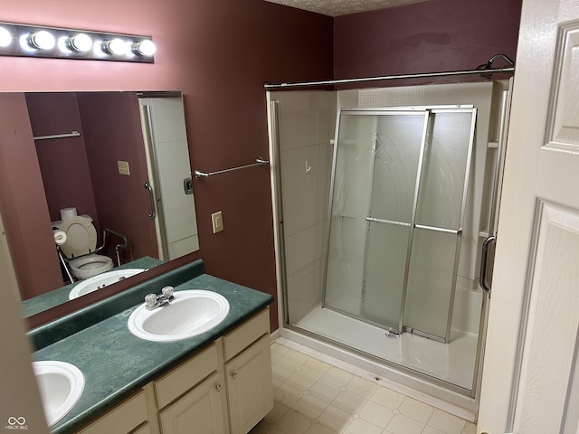 full bath with double vanity, toilet, a sink, a shower stall, and tile patterned floors