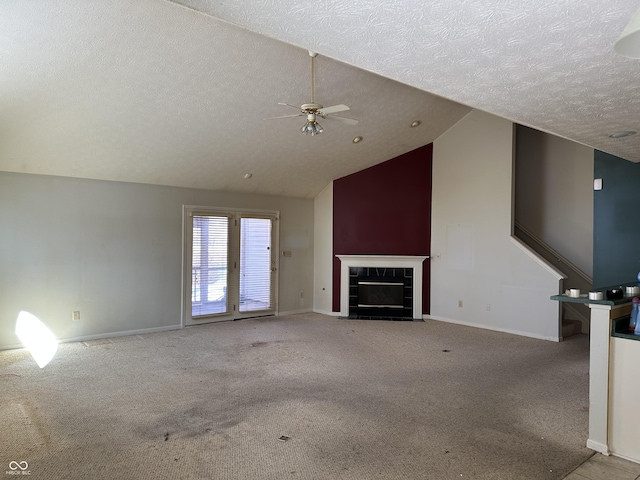 unfurnished living room with light colored carpet, vaulted ceiling, a textured ceiling, a tile fireplace, and baseboards