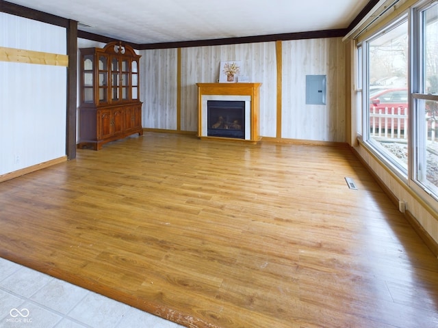 unfurnished living room with visible vents, light wood-style flooring, a fireplace with flush hearth, electric panel, and baseboards