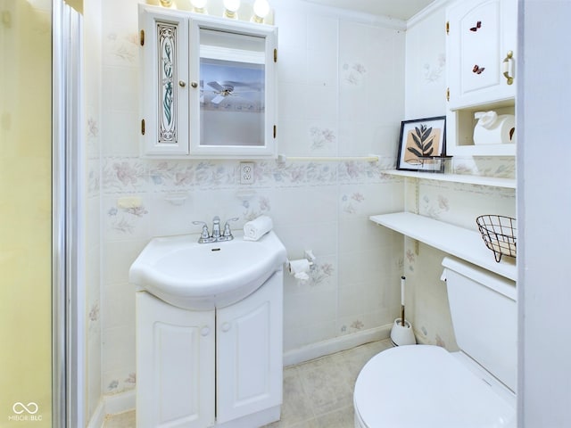 bathroom featuring toilet, tile walls, and vanity