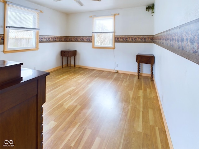 empty room with ceiling fan, light wood-style flooring, and baseboards