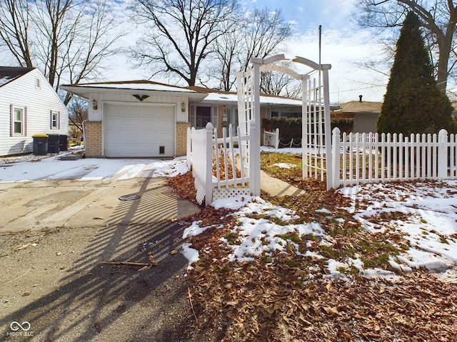 view of front of house featuring a garage, brick siding, fence, and driveway