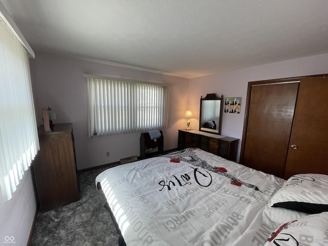 bedroom with baseboards, dark carpet, and a closet