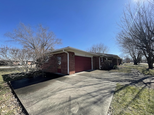 view of side of home with concrete driveway, brick siding, and an attached garage