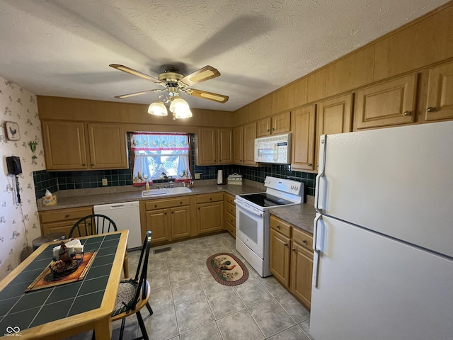 kitchen featuring tile countertops, white appliances, a textured ceiling, and wallpapered walls