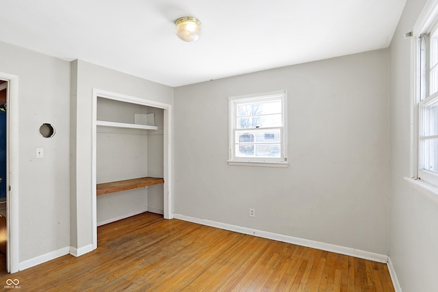 unfurnished bedroom featuring light wood finished floors, baseboards, and a closet