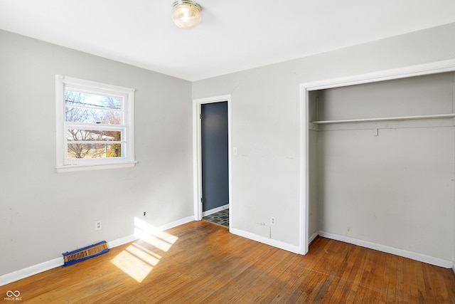 unfurnished bedroom featuring a closet, baseboards, and wood finished floors