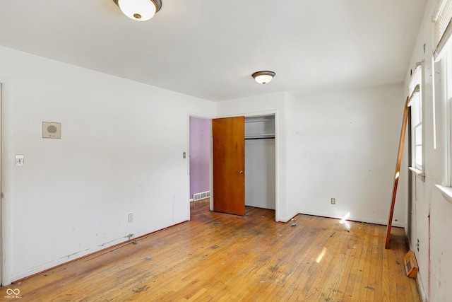 unfurnished bedroom with a closet, visible vents, and wood finished floors