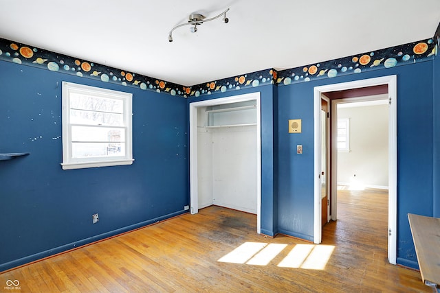 unfurnished bedroom with a closet, wood finished floors, and baseboards