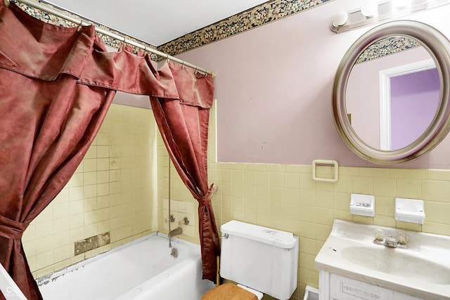 bathroom with a wainscoted wall, tile walls, toilet, shower / bath combo with shower curtain, and vanity