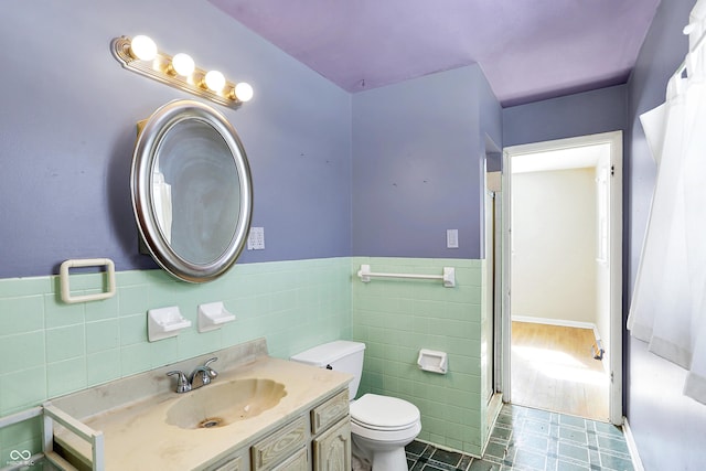 bathroom featuring tile walls, toilet, wainscoting, vanity, and tile patterned floors