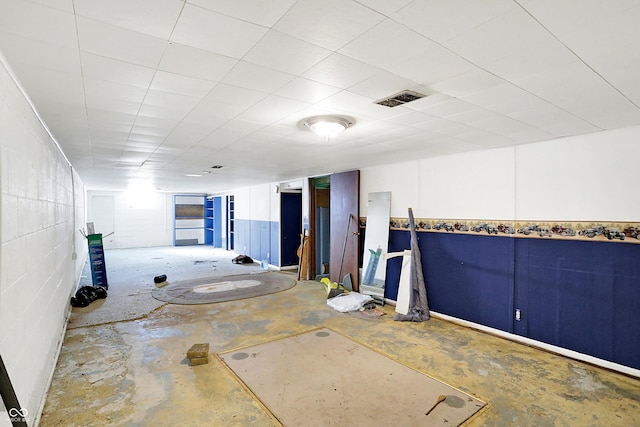 interior space with concrete flooring, visible vents, and concrete block wall