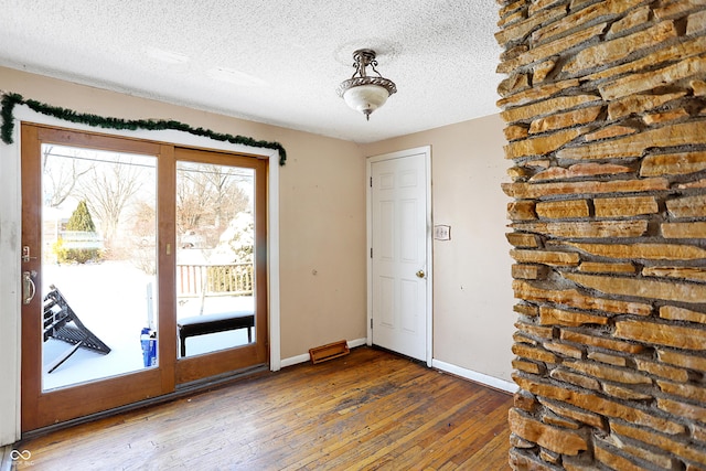 doorway featuring baseboards, dark wood finished floors, and a textured ceiling