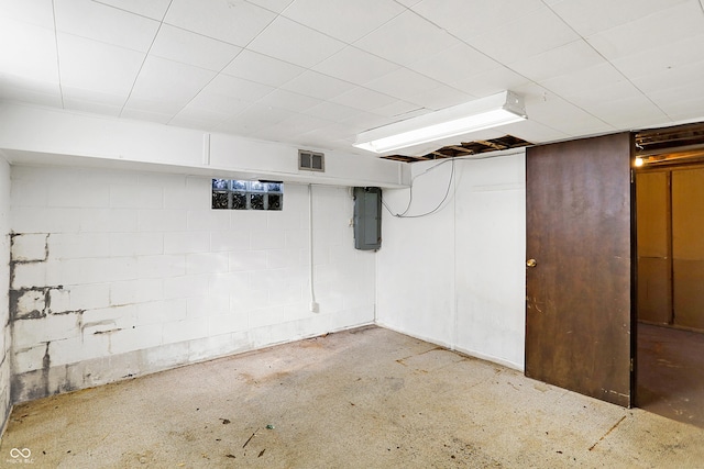 finished basement with visible vents, electric panel, and concrete block wall