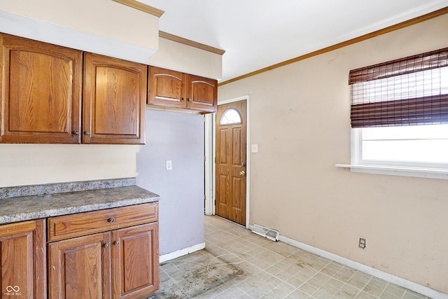 kitchen featuring visible vents, baseboards, light countertops, ornamental molding, and brown cabinets