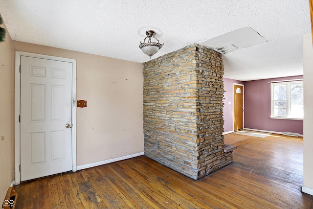 spare room with dark wood-style floors, visible vents, a textured ceiling, and baseboards