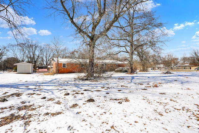 yard covered in snow featuring a carport, an outdoor structure, a garage, and a storage unit