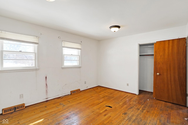 unfurnished bedroom with a closet, dark wood-style flooring, and visible vents