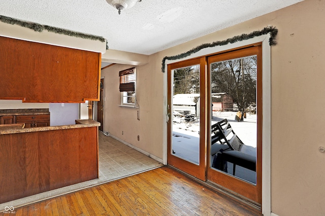 kitchen with plenty of natural light, a textured ceiling, baseboards, and wood finished floors