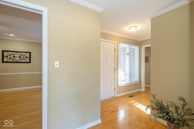 entryway with visible vents, crown molding, light wood-style flooring, and baseboards