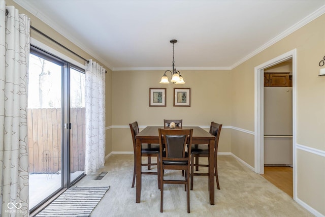 dining room featuring light colored carpet, visible vents, ornamental molding, a chandelier, and baseboards