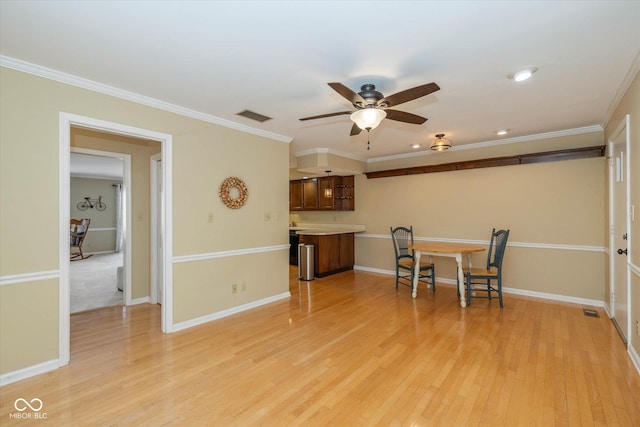 dining room featuring crown molding, visible vents, light wood-style flooring, a ceiling fan, and baseboards