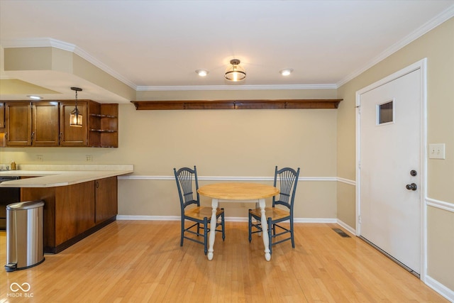 dining space featuring light wood-type flooring, crown molding, and baseboards