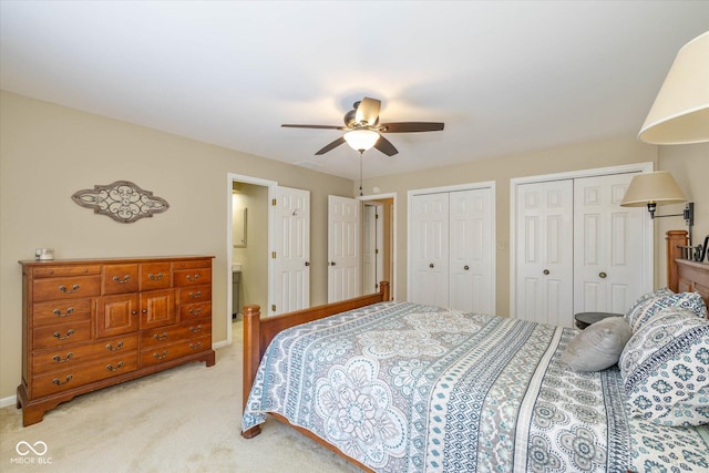 bedroom with ceiling fan, two closets, and light colored carpet