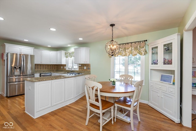 kitchen with appliances with stainless steel finishes, light wood-type flooring, white cabinetry, and tasteful backsplash