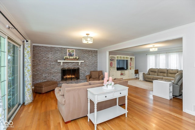 living room with light wood finished floors, brick wall, a fireplace, and crown molding