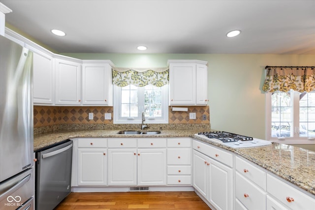 kitchen with stainless steel appliances, plenty of natural light, a sink, and visible vents