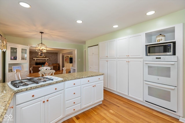 kitchen with decorative light fixtures, light wood finished floors, recessed lighting, white cabinetry, and white appliances