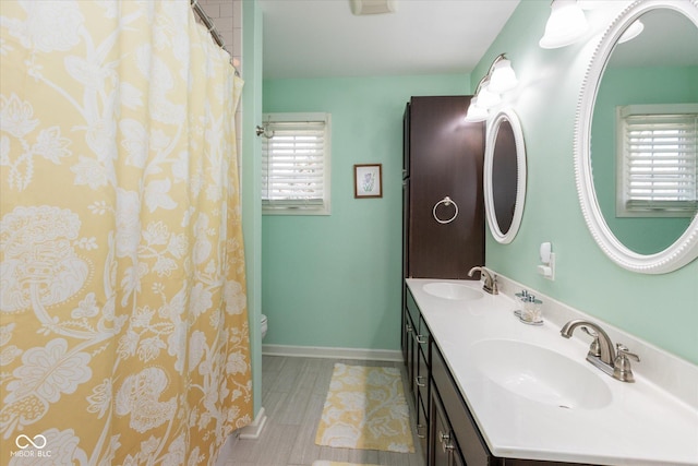 full bath with a wealth of natural light, baseboards, and a sink