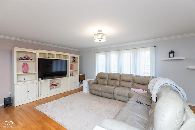 living room with light wood-style floors, crown molding, and baseboards