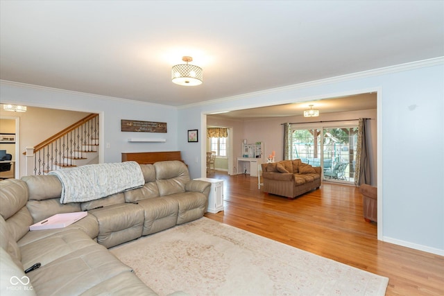 living room featuring baseboards, stairway, light wood-style flooring, and crown molding