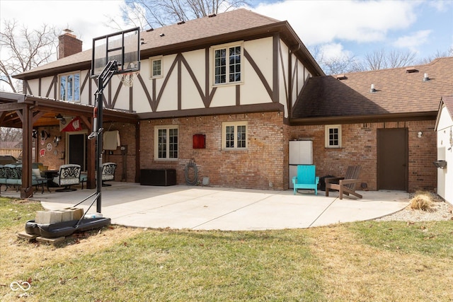 rear view of house featuring a patio area, a chimney, brick siding, and stucco siding