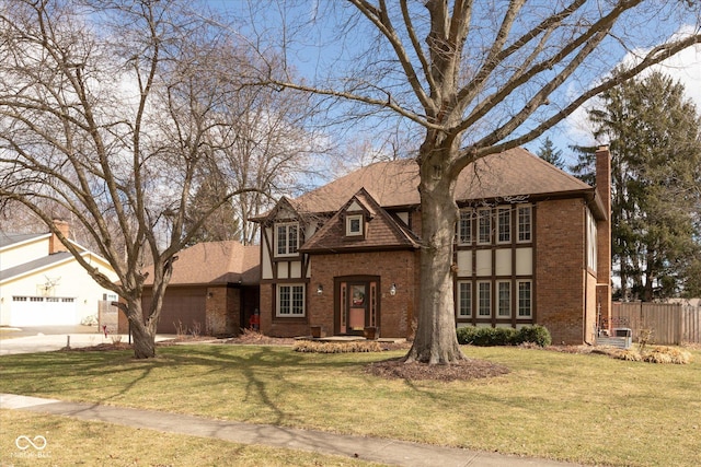 tudor house with a garage, brick siding, fence, and a front lawn