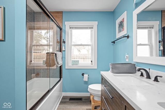 bathroom with a healthy amount of sunlight, baseboards, visible vents, and wood finished floors