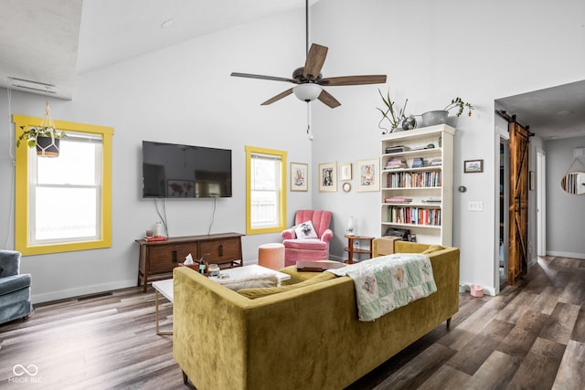 living area featuring ceiling fan, high vaulted ceiling, a barn door, wood finished floors, and baseboards