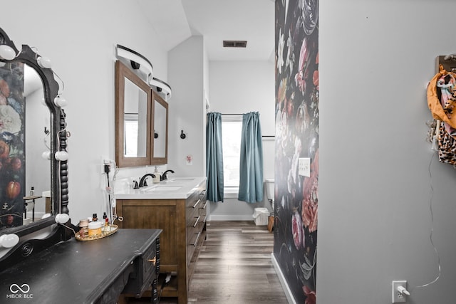 bathroom with visible vents, vaulted ceiling, vanity, wood finished floors, and baseboards