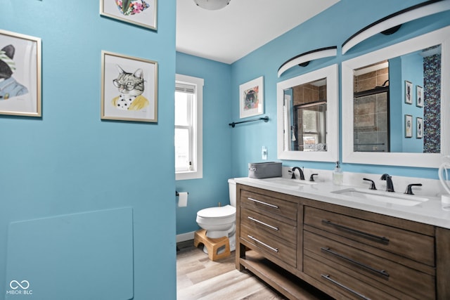 full bathroom with a tile shower, double vanity, a sink, and toilet