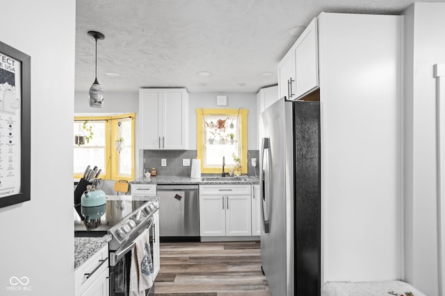 kitchen with stainless steel appliances, white cabinetry, a sink, and decorative backsplash