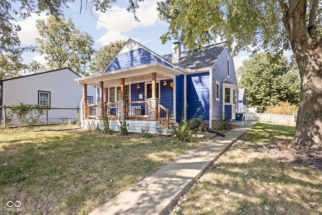 view of front of home with a front lawn, a chimney, fence, and a porch